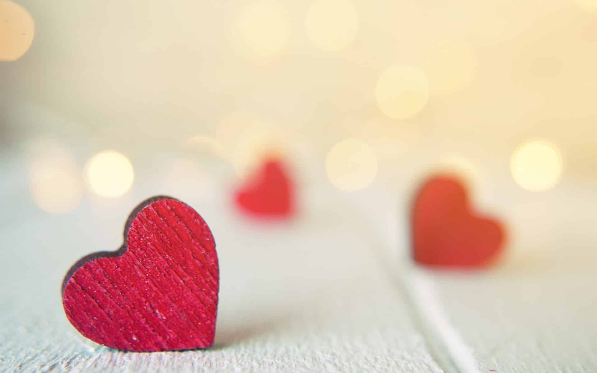 Wooden red hearts sitting on a white wooden table