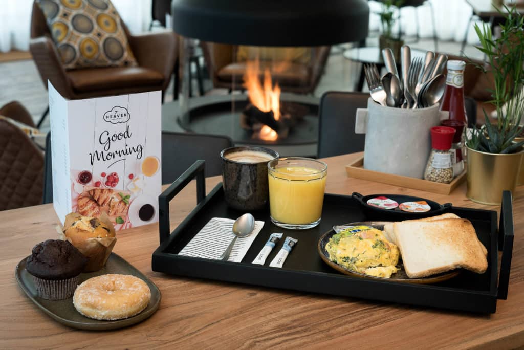 Délicieux petit-déjeuner avec jus d'orange, œufs, toasts et beignets au PREMIER SUITES PLUS Anvers.