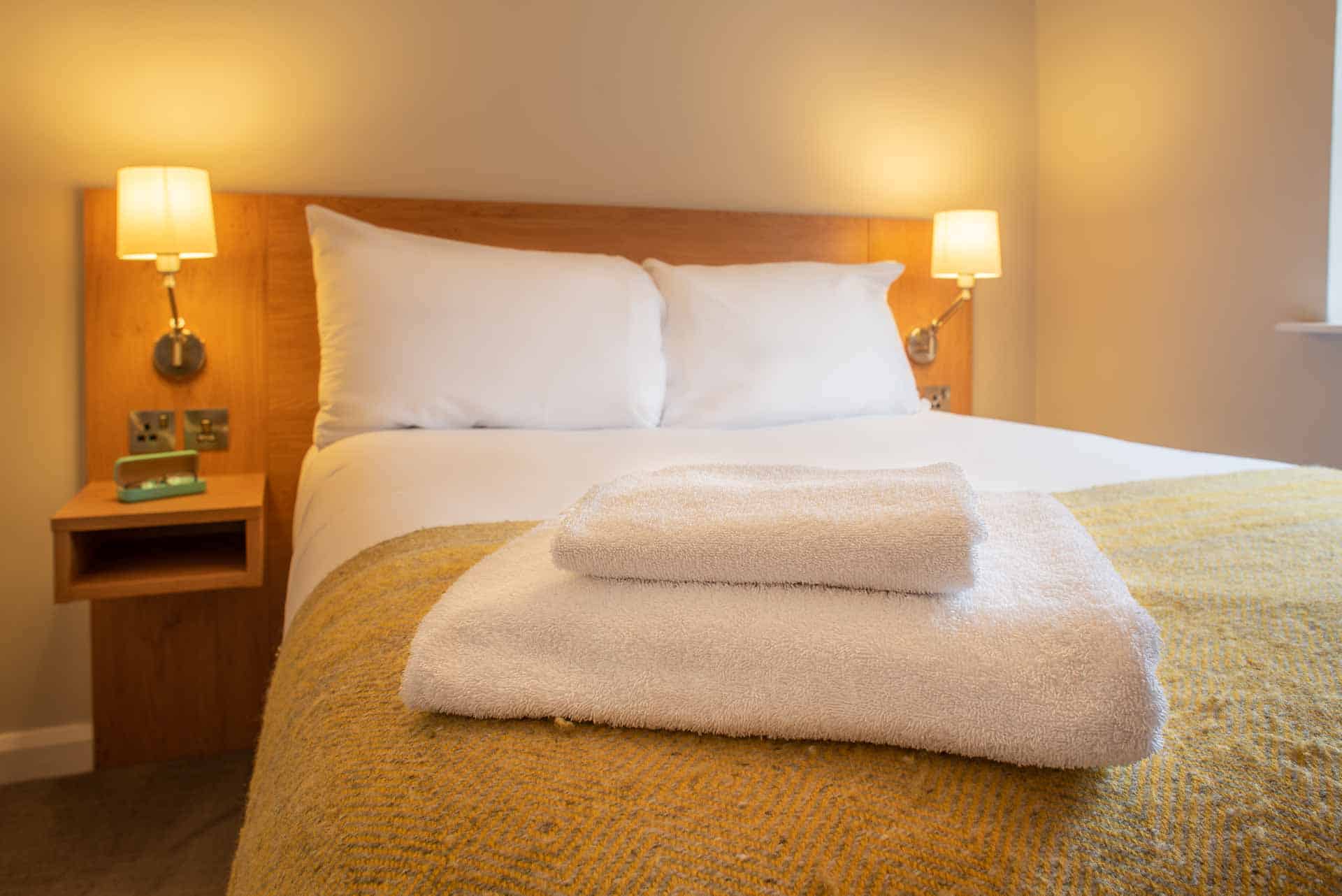 Flauschige Handtücher auf dem Bett ausgelegt bei PREMIER SUITES Reading