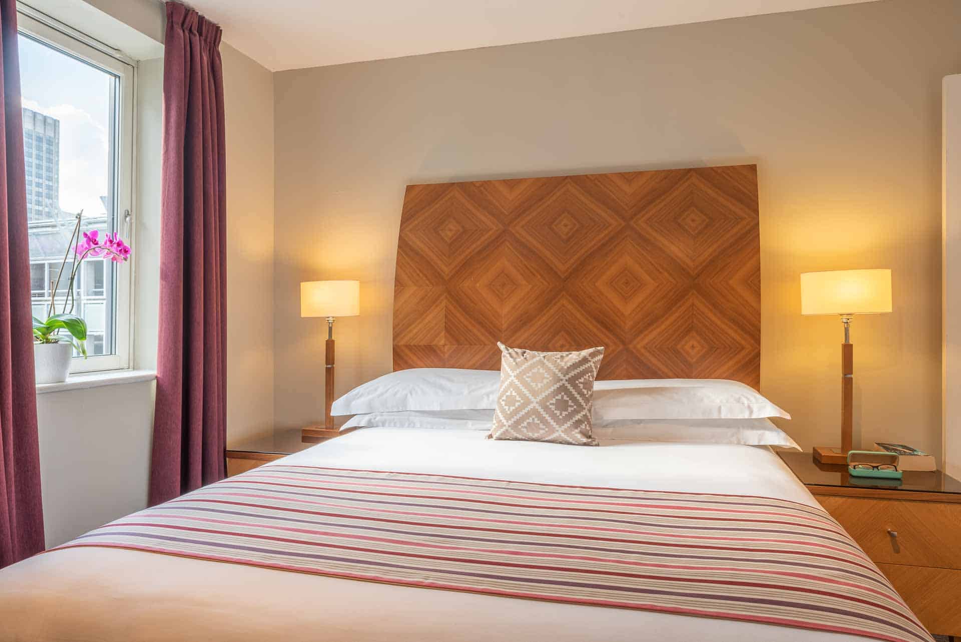 Large double bed with natural light and modern decor at PREMIER SUITES Birmingham