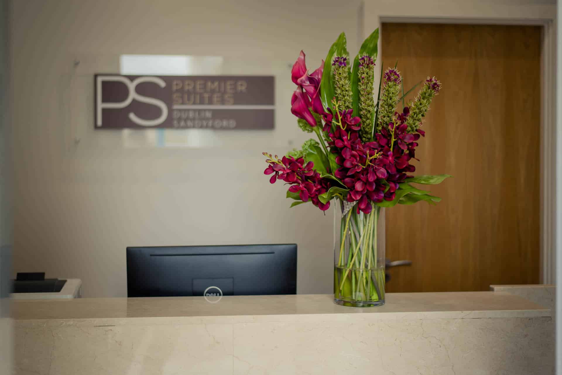 PREMIER SUITES Dublin Sandyford (Rezeption mit Blumen und PS-Logo)