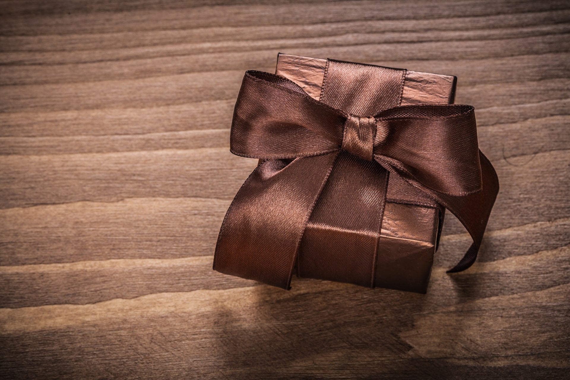 Fond marron avec un cadeau emballé dans du papier marron et un ruban marron