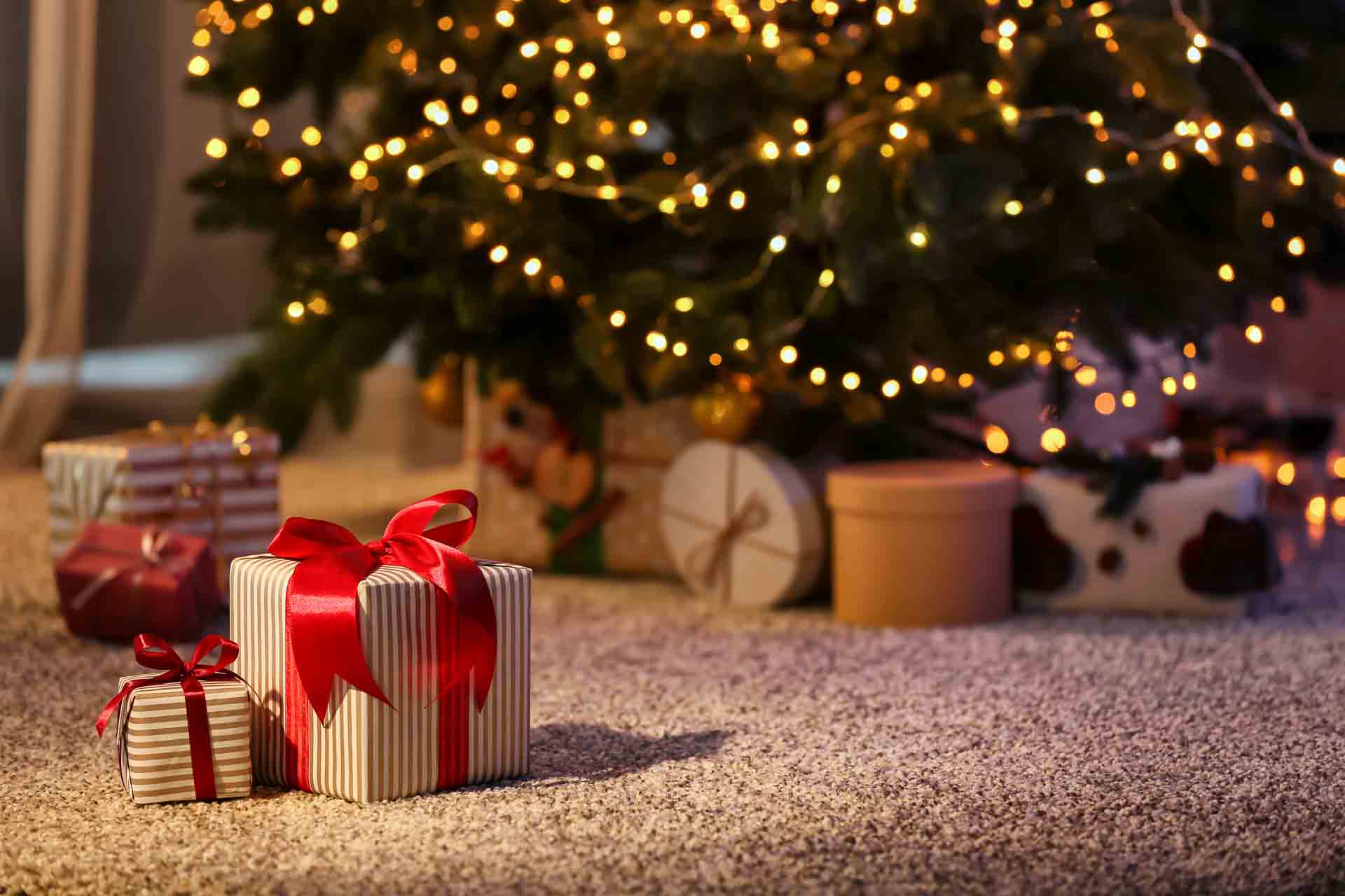 Schöne Weihnachtsgeschenkboxen auf dem Boden neben dem Tannenbaum im Zimmer