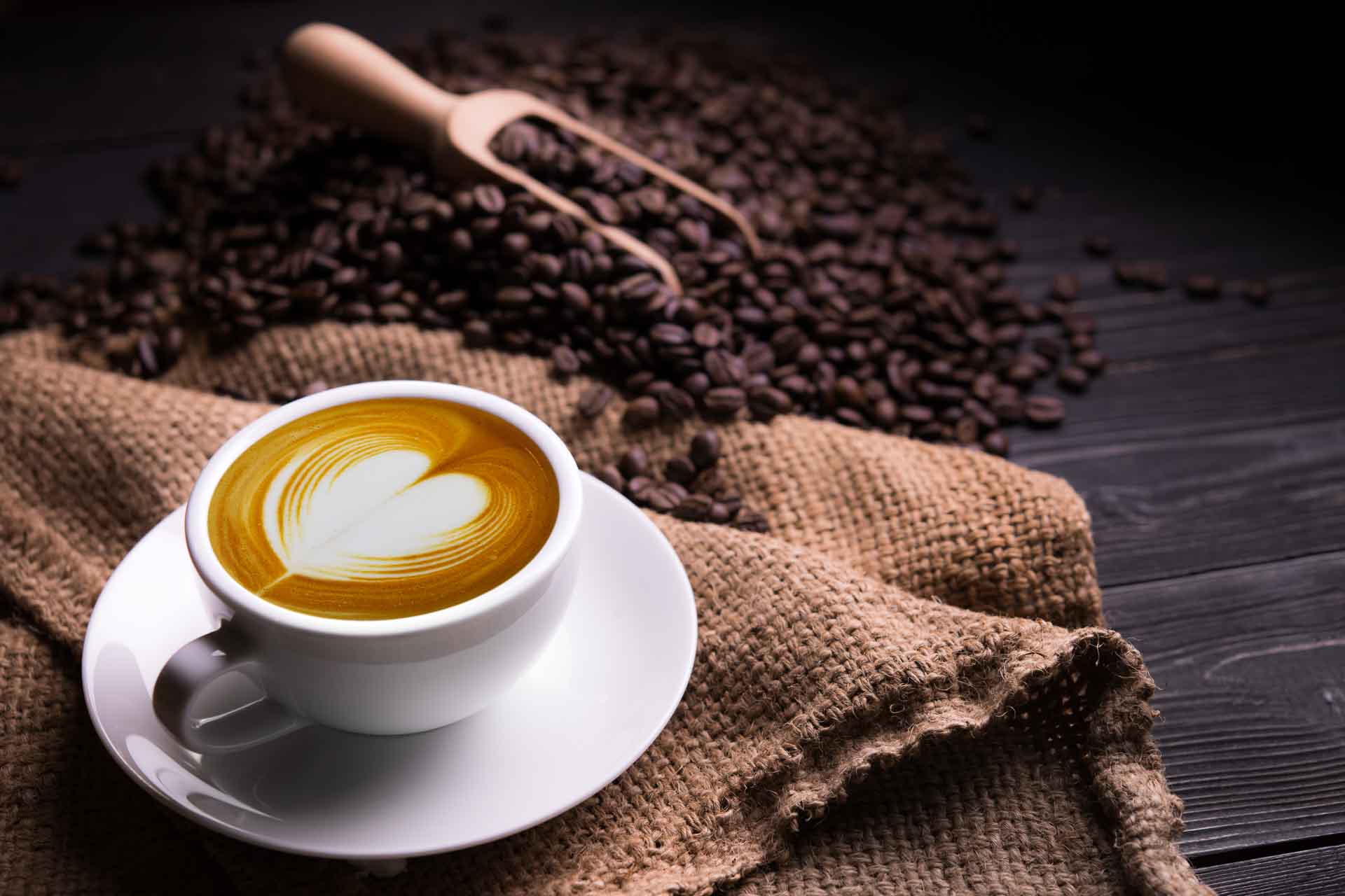 Tasse de café latte avec forme de cœur et grains de café sur fond de vieux bois
