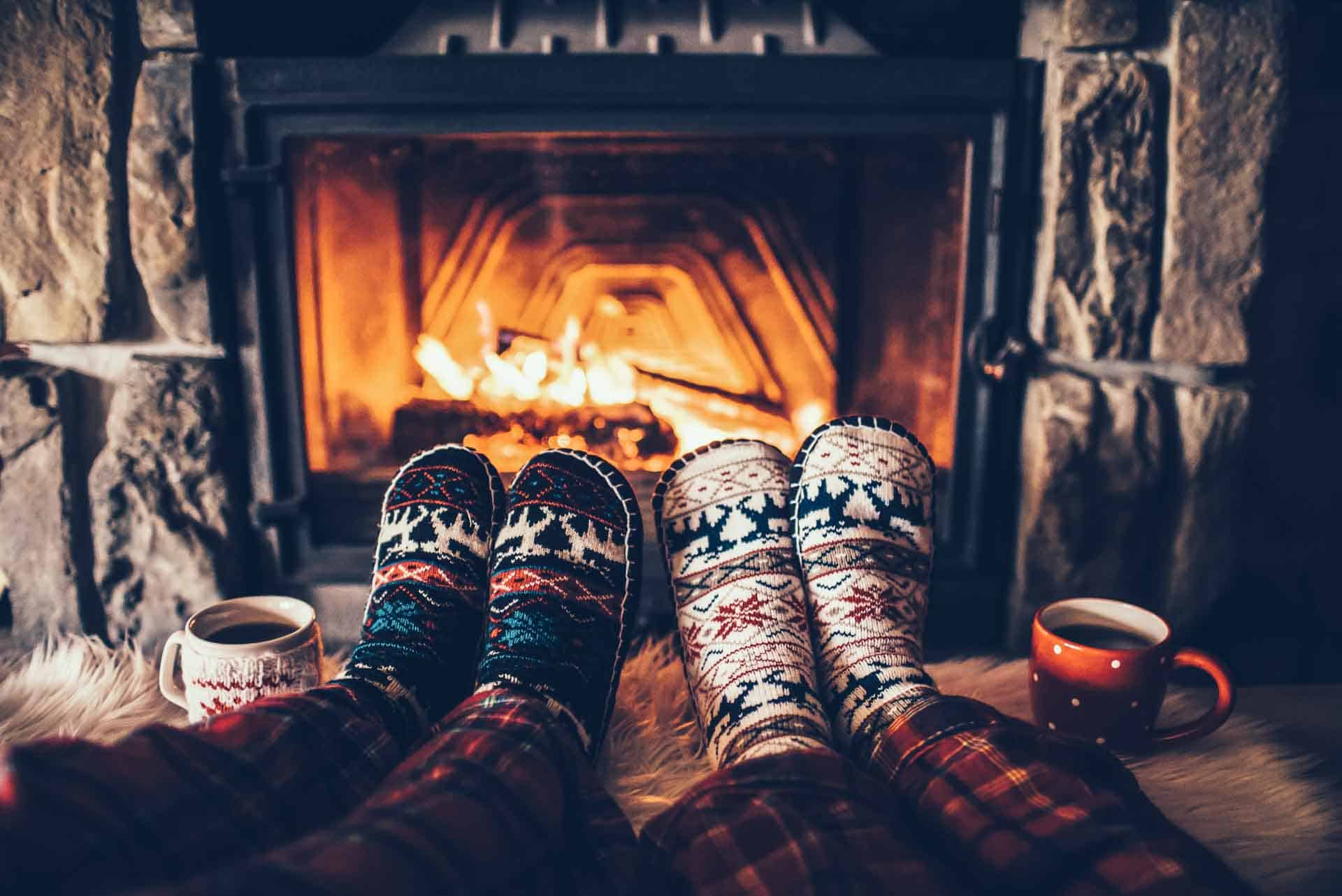 Feet in woollen socks by the Christmas fireplace.