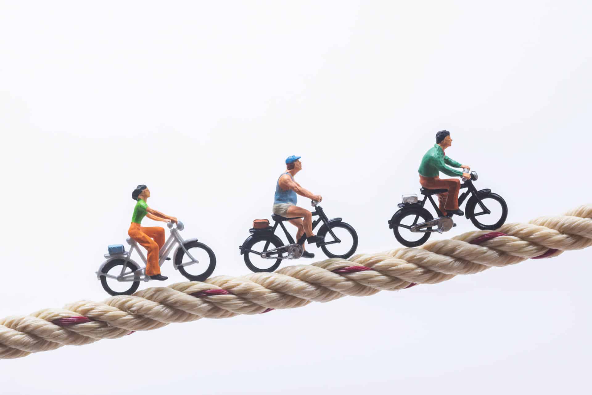 Miniature people cycling on rope