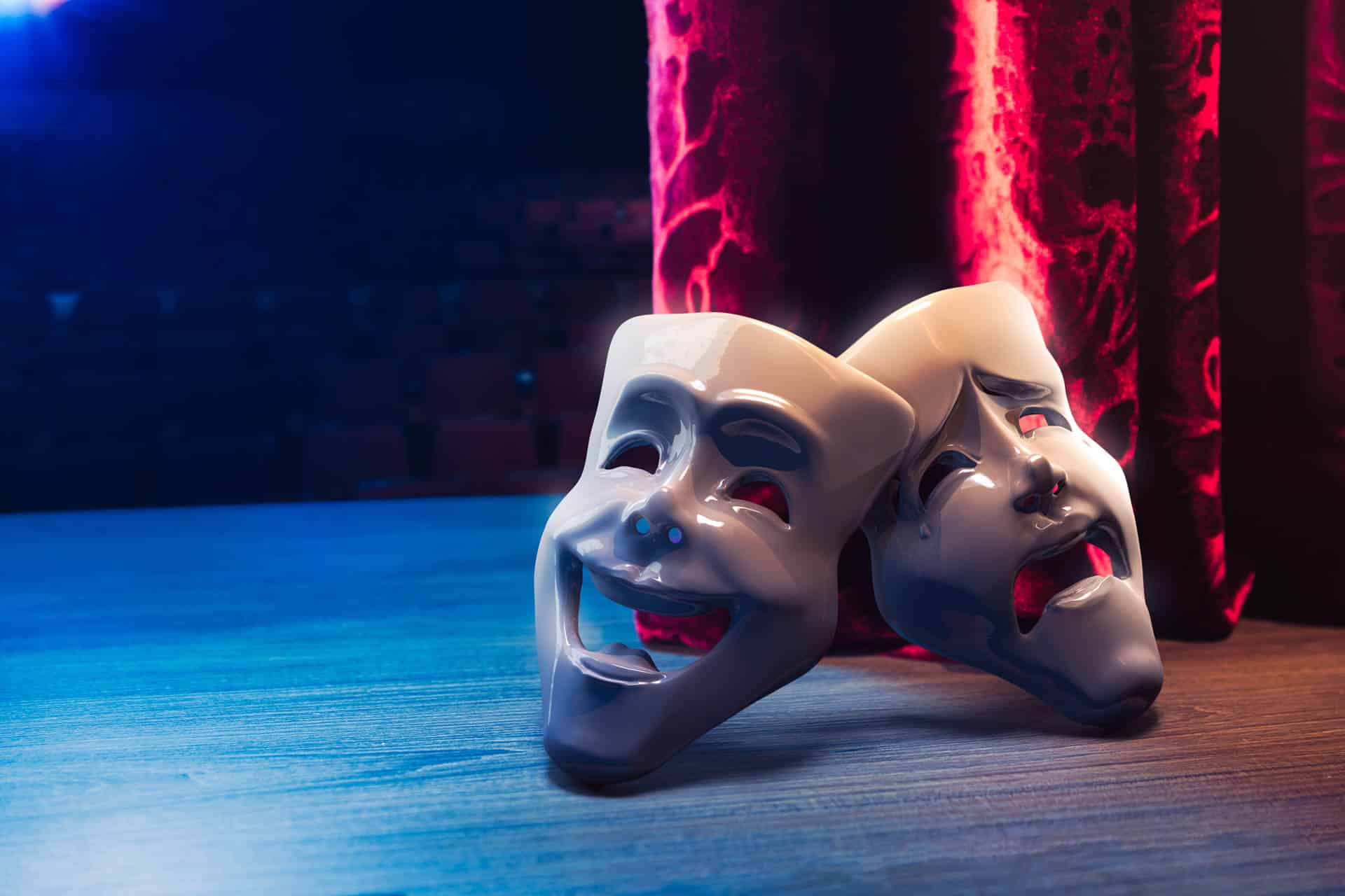 Theatermaskers liggen op het toneel achter het rode gordijn