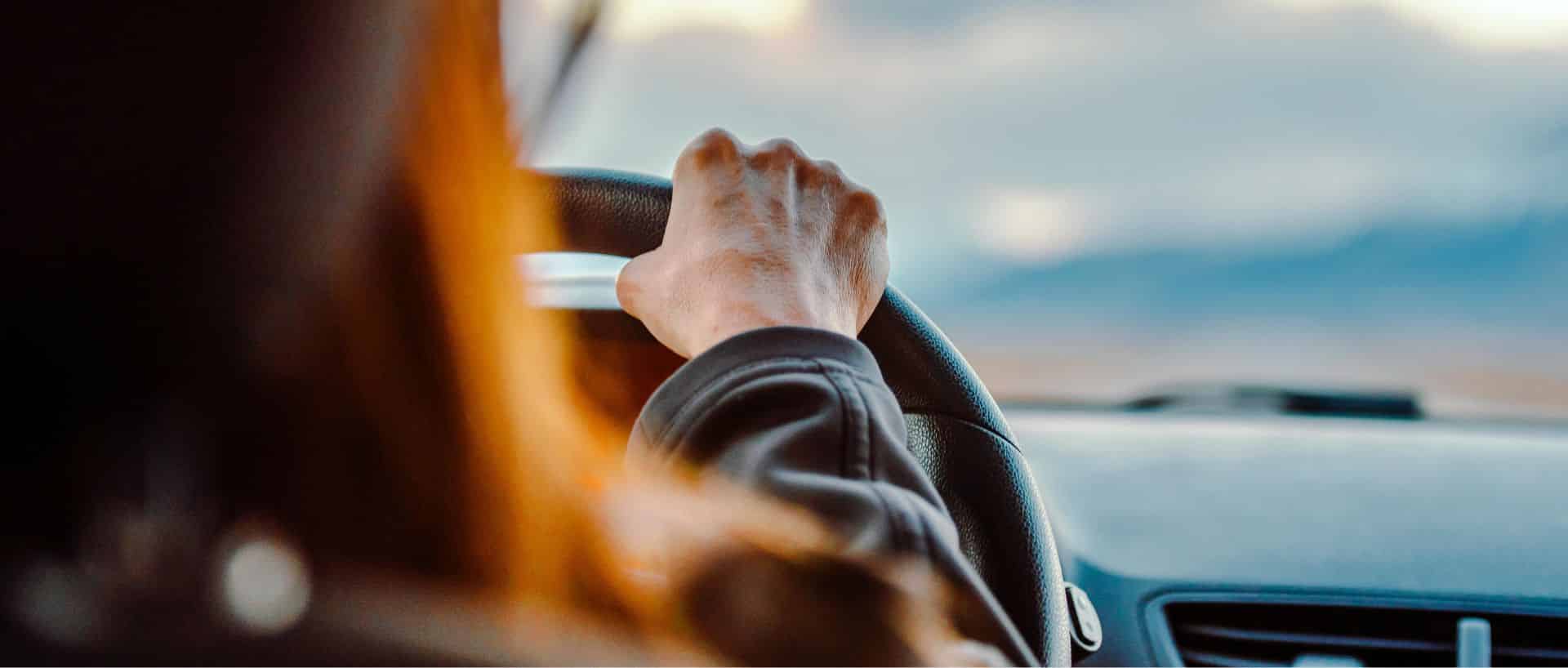 Femme conduisant une voiture avec la main sur le volant