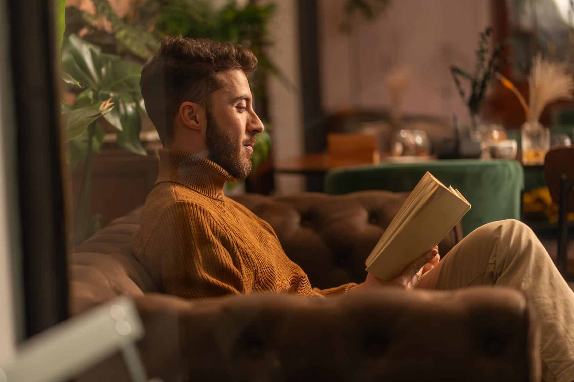 Man relaxing reading a book on cosy sofa