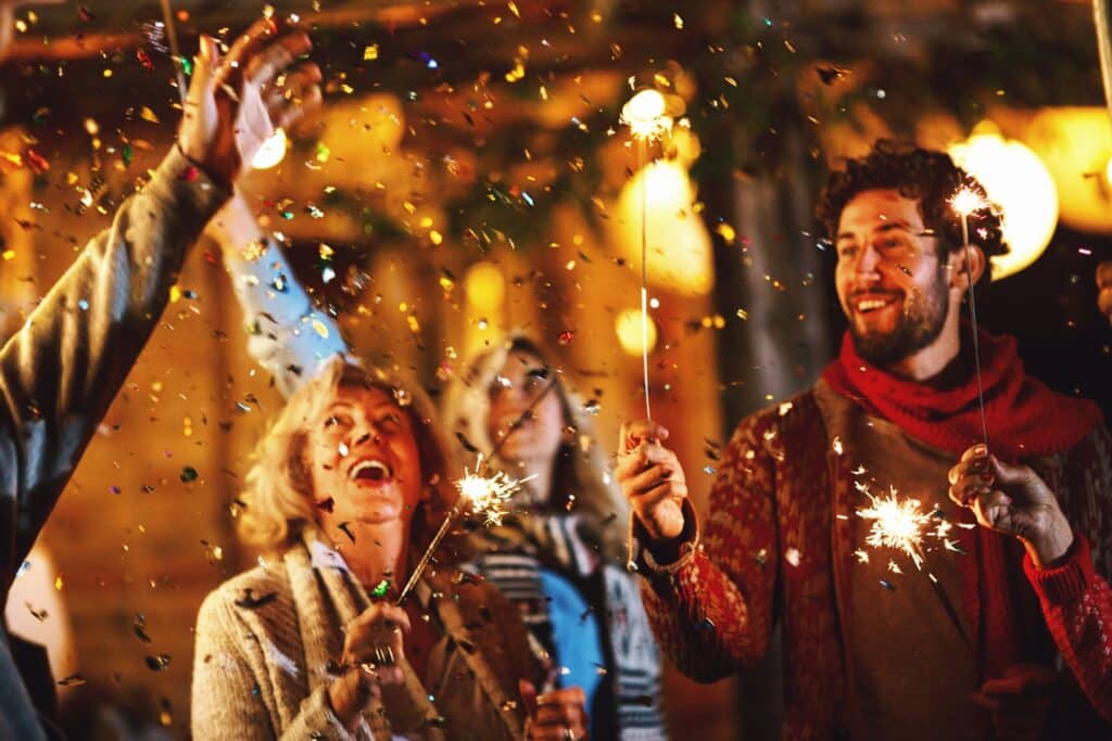 groep mensen steekt samen vuurwerk aan en lacht terwijl ze naar de confetti in de lucht kijken