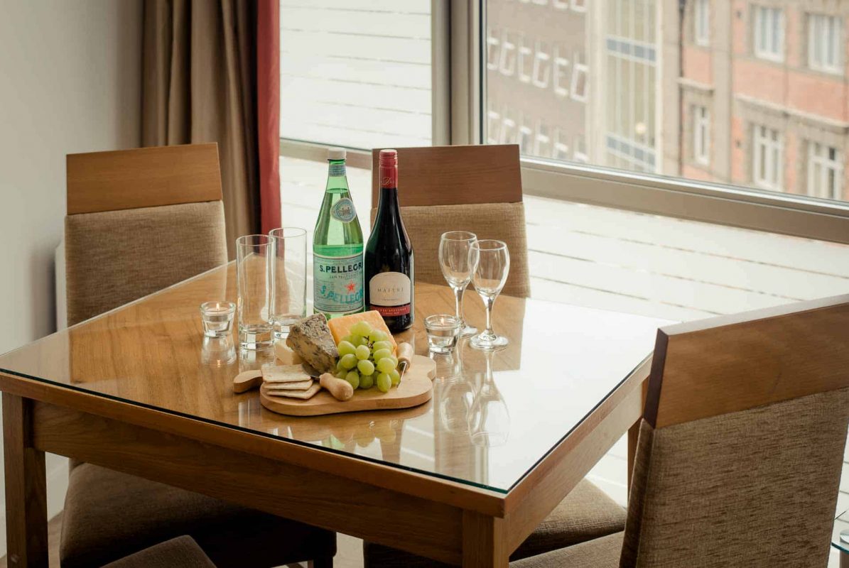 Dining table set with wine and cheese at PREMIER SUITES Liverpool