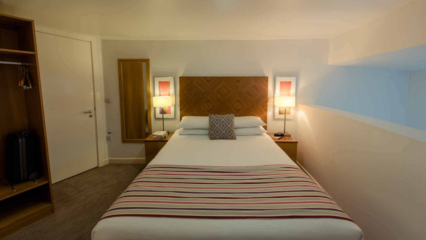 Large double bed with two bedside lamps lit at PREMIER SUITES Liverpool