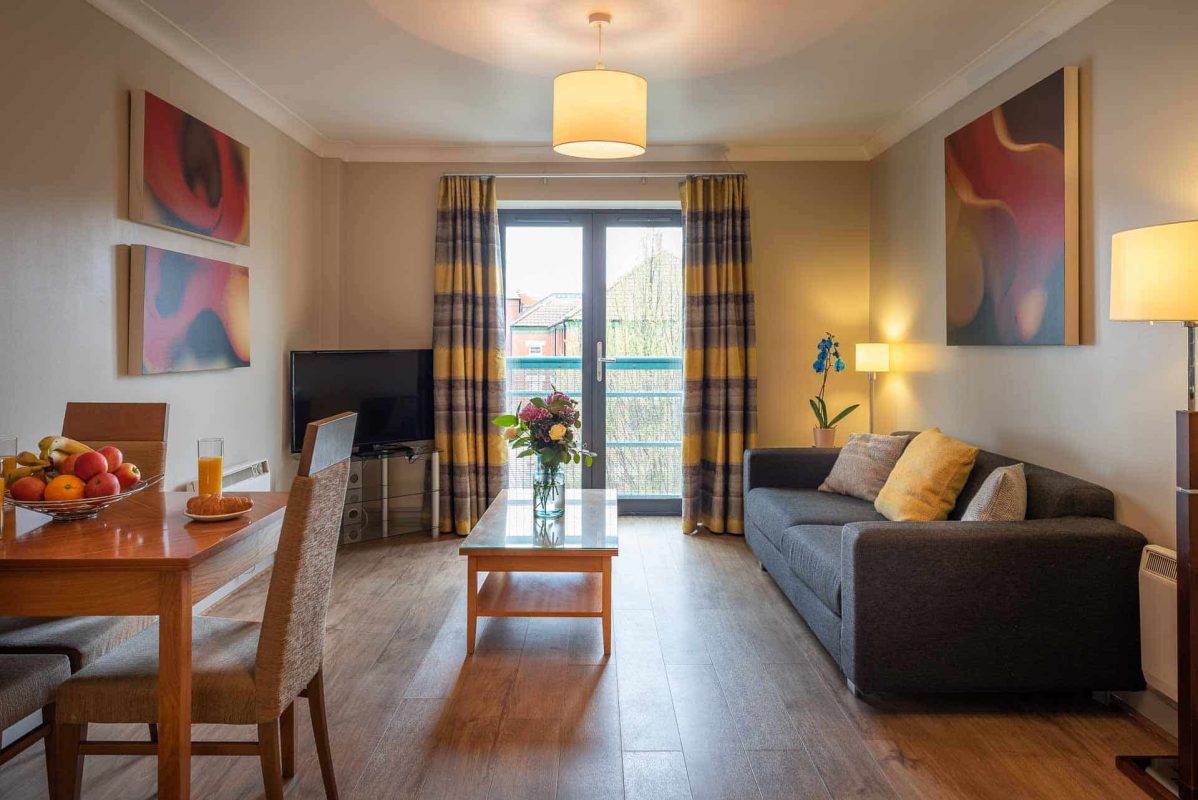 Open plan sitting room with sofa, dining table and TV at PREMIER SUITES Bristol Redcliffe